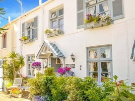 Un edificio bianco con diverse finestre, alcune dotate di persiane, e un piccolo portico con una lampada.
