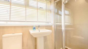 A bathroom with a toilet, sink, and glass shower enclosure.