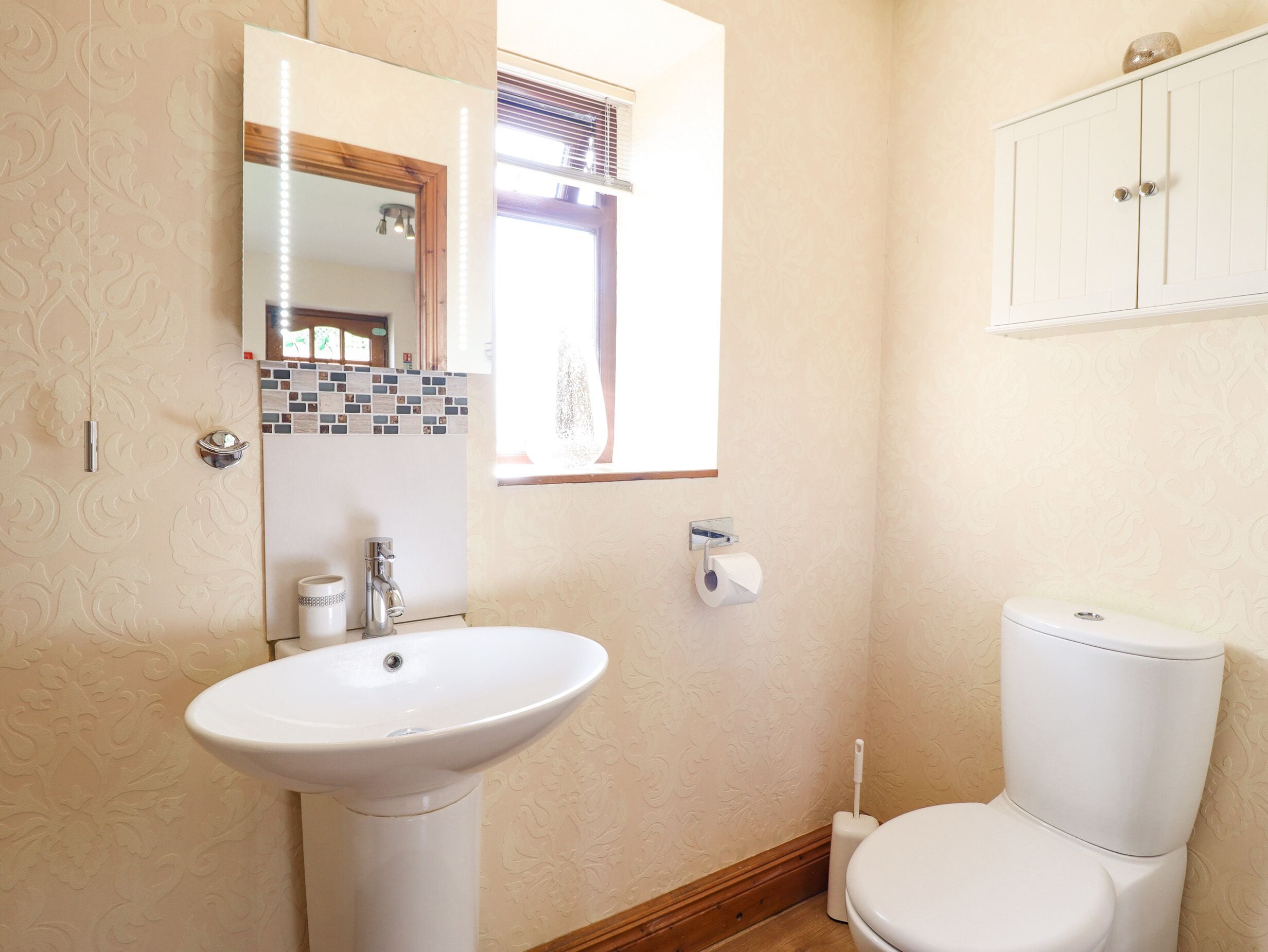 A bathroom with a sink, toilet, and a mirror.