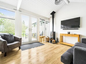 Ein modernes Wohnzimmer mit Kamin, einem an der Wand befestigten Fernseher und einer Glastür, die zu einem Außenbereich führt.