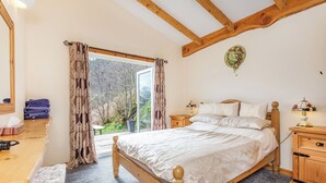 Une chambre à coucher avec un lit en bois, un bureau et une fenêtre avec des rideaux.