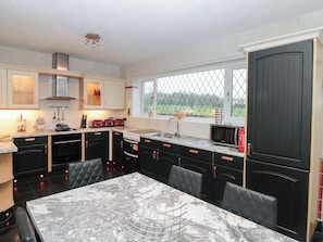 A modern kitchen with a marble countertop, black cabinets, and a dining area with a marble table.