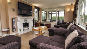 A living room with a fireplace, a television, and a large window.