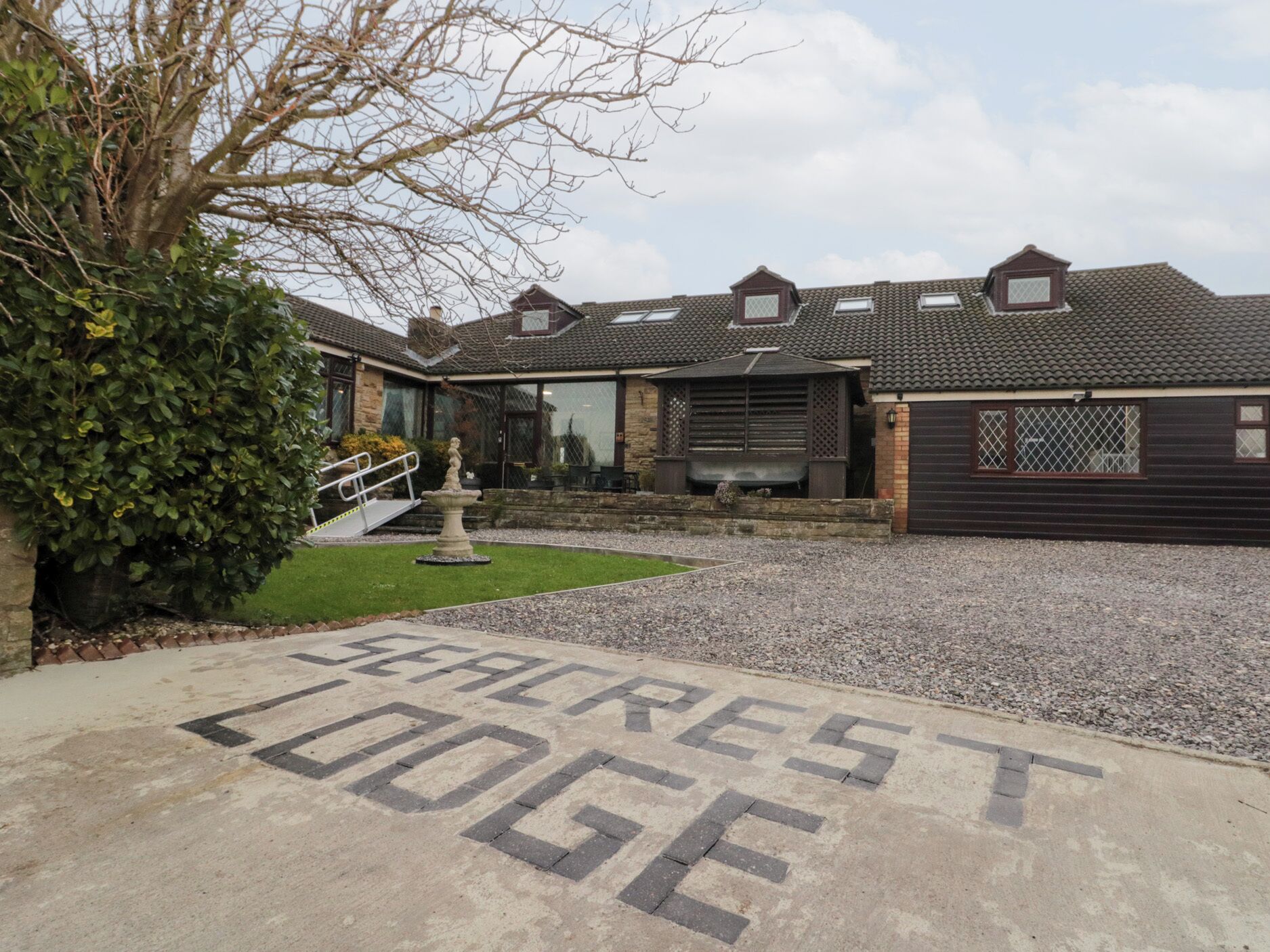 A building labeled "Seaclrest Lodge" with a gravel driveway and a small garden area.