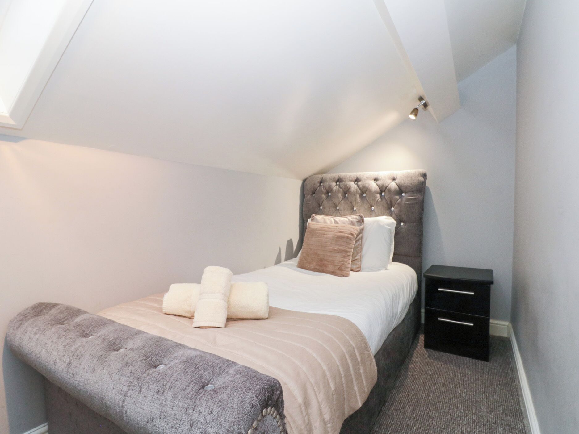 A bedroom with a bed, bedside tables, and a bench.