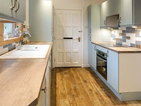 Una cocina moderna con encimera de madera, un lavabo y un horno empotrado.