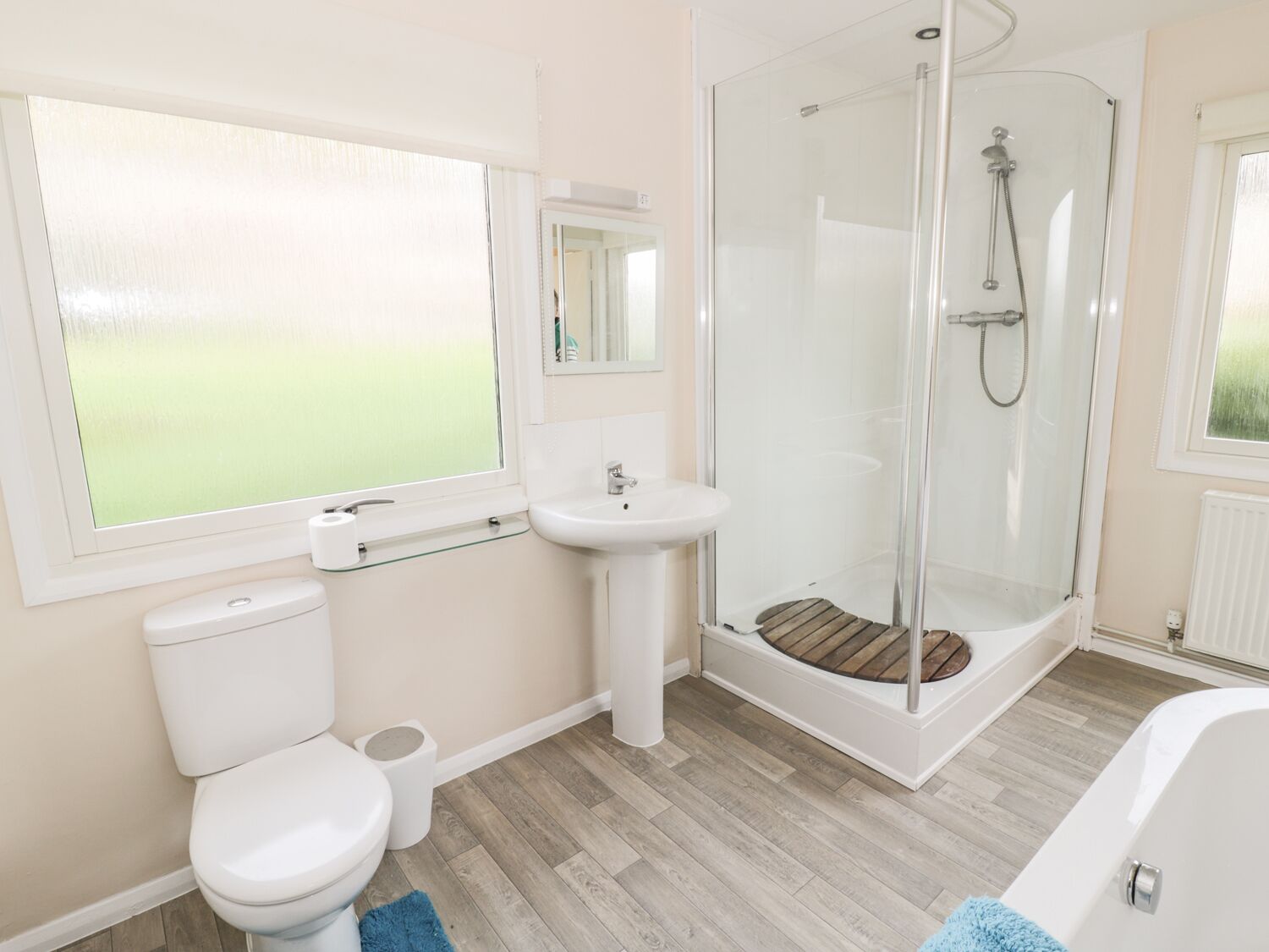 Un baño moderno con inodoro, lavamanos, cabina de ducha con mampara de vidrio y bañera.