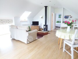 Una sala de estar moderna con sofá, televisor, chimenea y comedor con mesa y sillas.