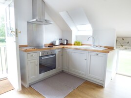 Una cocina moderna con horno empotrado, cocina a gas y campana extractora de acero inoxidable.