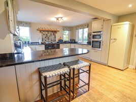 A kitchen with a central island, bar stools, a built-in oven, and a refrigerator.
