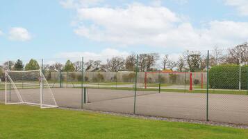 A fenced sports field with a goalpost, a bench, and a sign in the background.