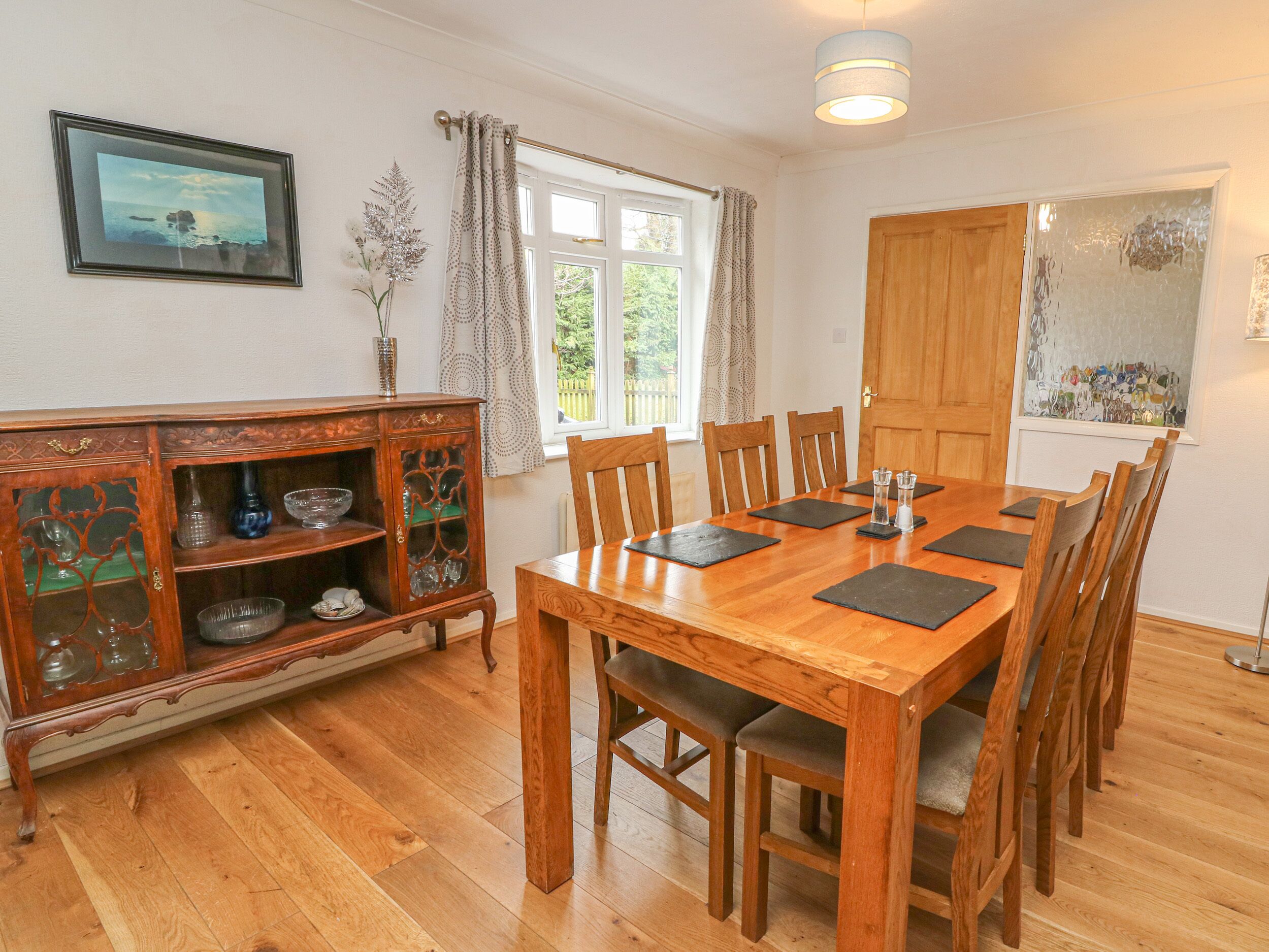 A dining room with a wooden table, chairs, and a cabinet with glass doors.