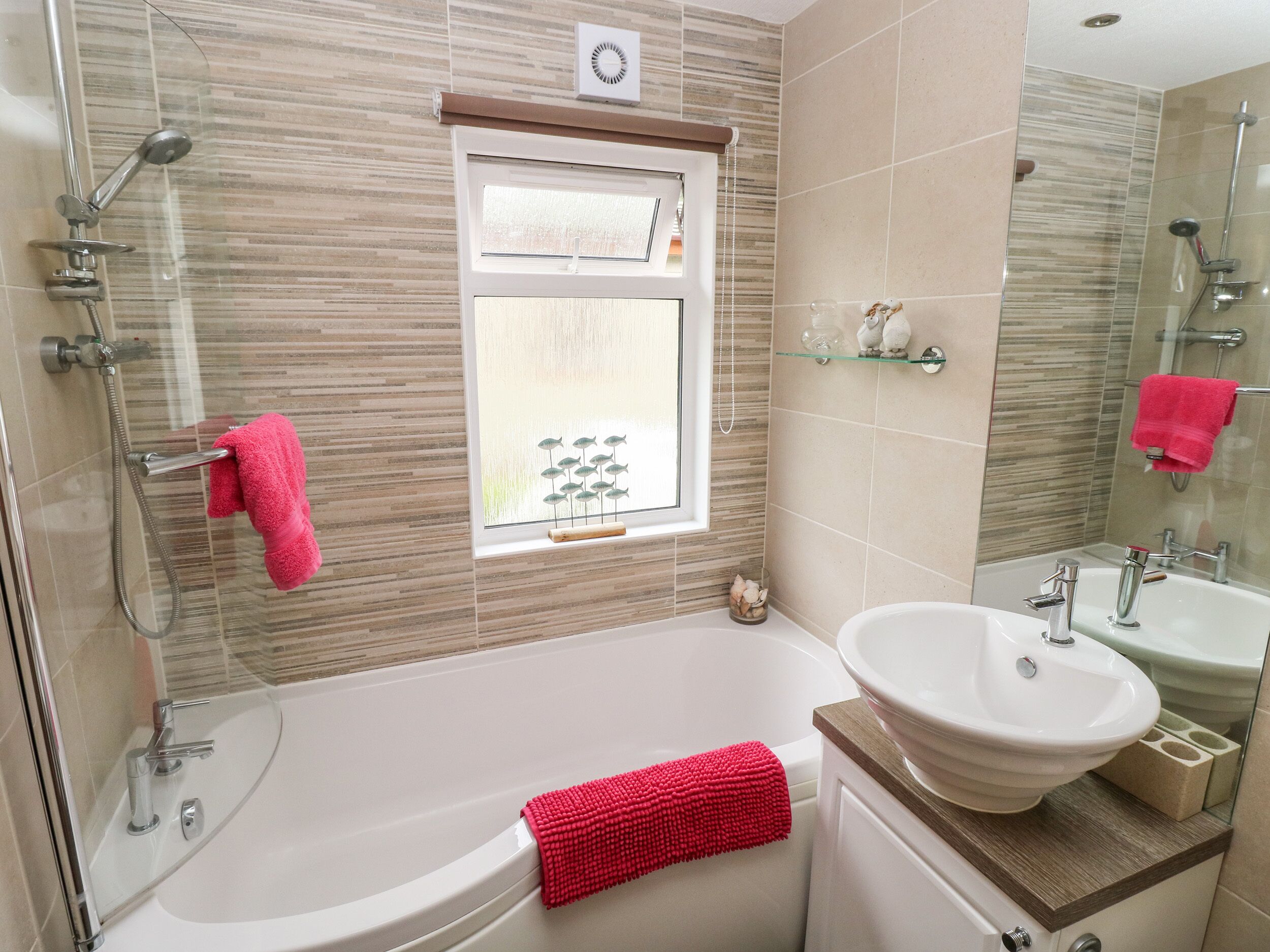 A modern bathroom with a glass-enclosed shower, a large bathtub, a white sink, and a mirror.
