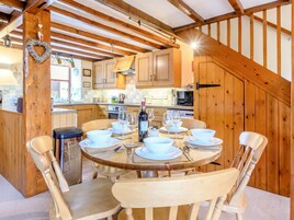 Un interior de madera con una mesa de comedor preparada para cuatro personas, rodeada de sillas de madera.