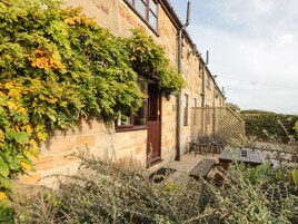 Un edificio de piedra con puerta de madera y un pequeño patio con mesas al aire libre.