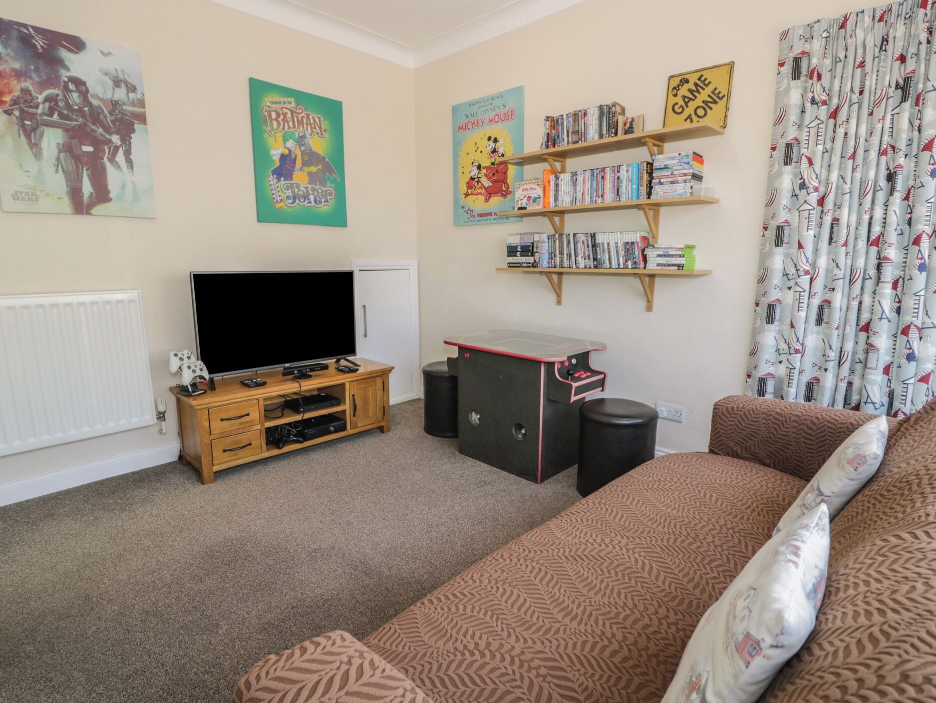 A living room with a television, bookshelf, and posters on the wall.