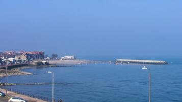A coastal road with parked cars and a pedestrian walkway alongside the sea.