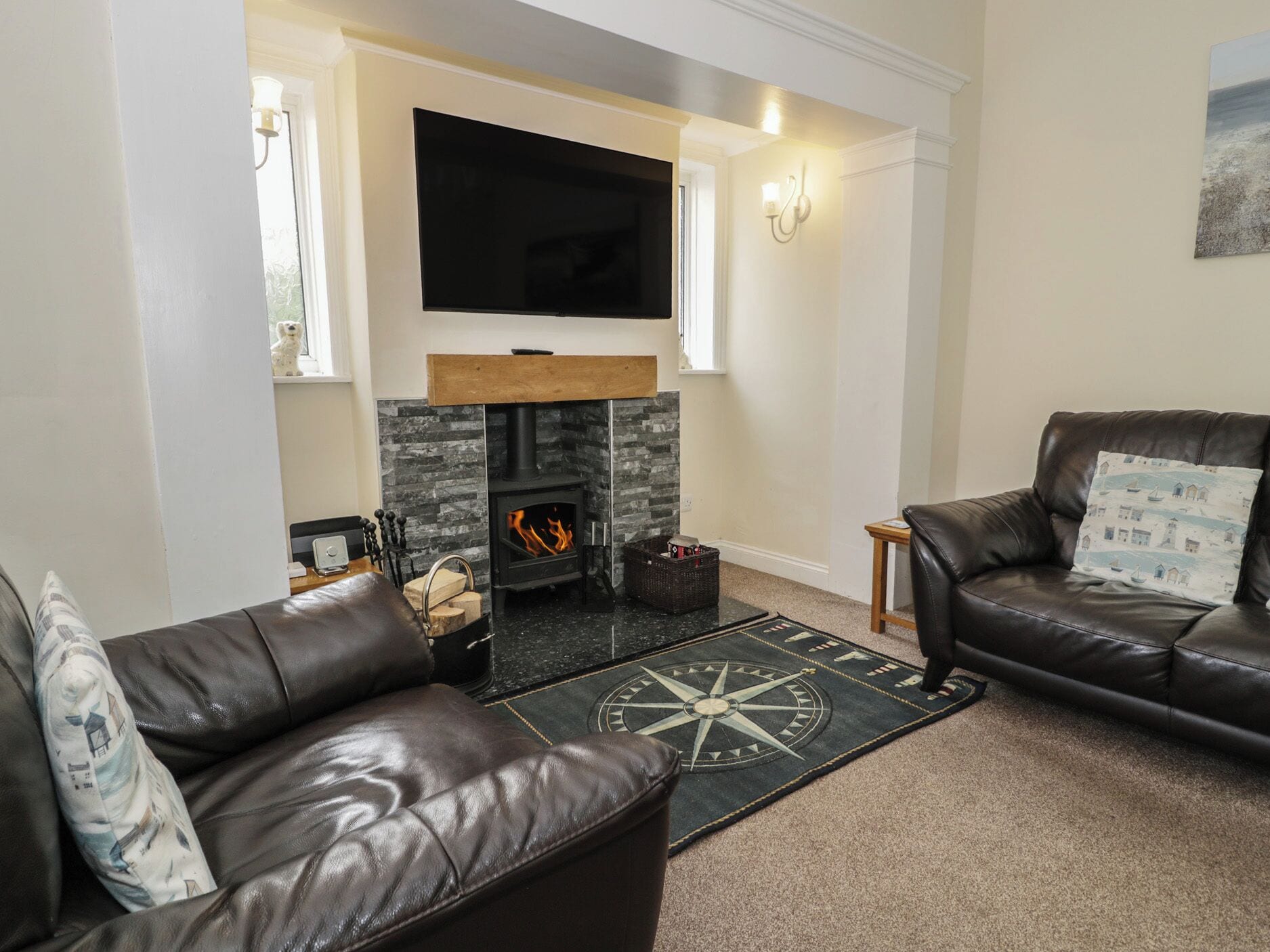 A living room with a fireplace, leather sofas, a flat-screen TV, and a decorative rug.