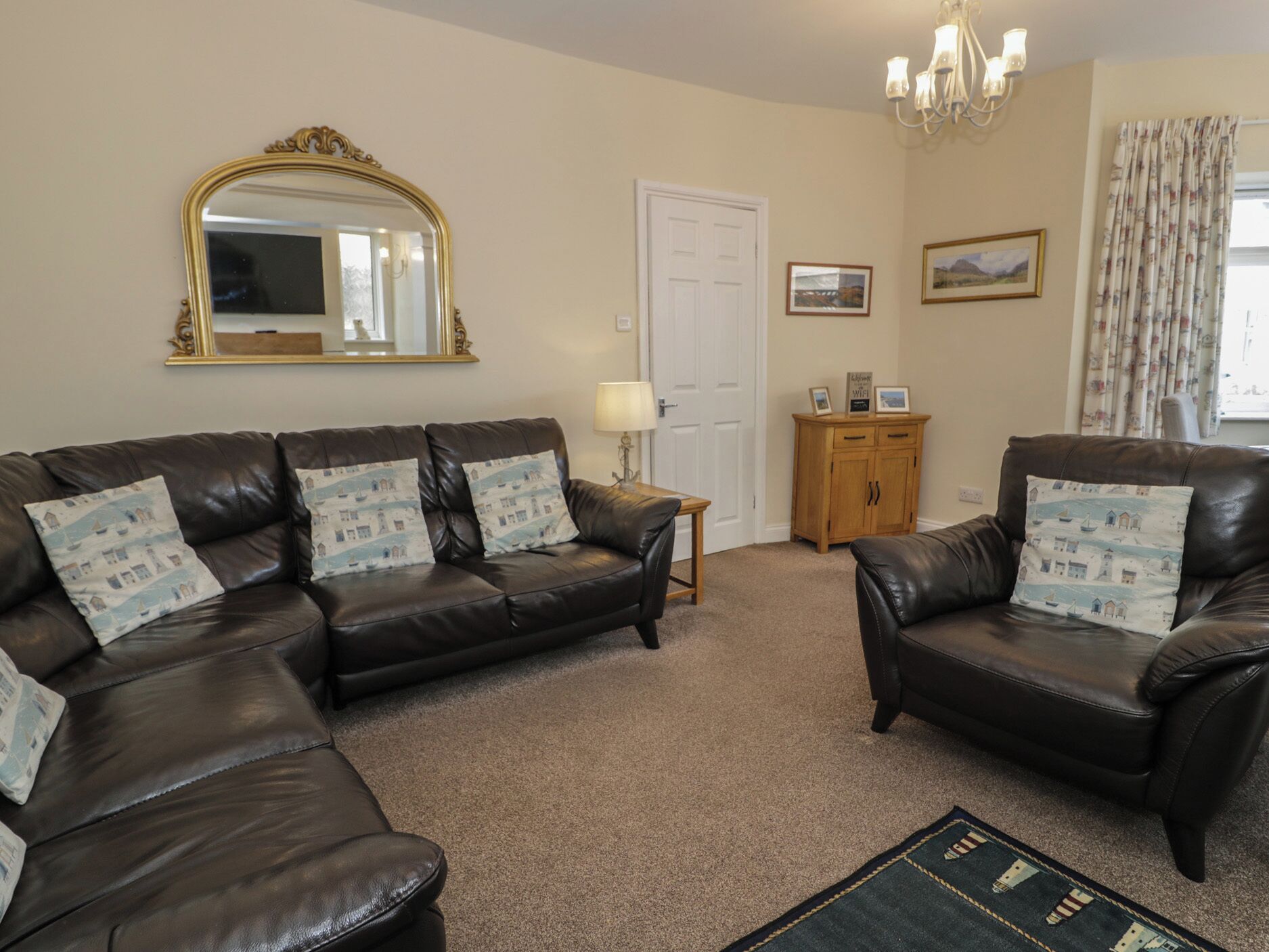 A living room with two leather sofas, a mirror, a lamp, a wooden cabinet, and a door.