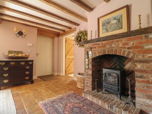 A room with a fireplace, wooden beams, a dresser, and a rug. - Just A Cottage, Newlands Farm (Alfreton)
