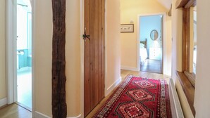 A hallway with a wooden door, a red patterned rug, and a ceiling light. - Just A Cottage, Newlands Farm (Alfreton)