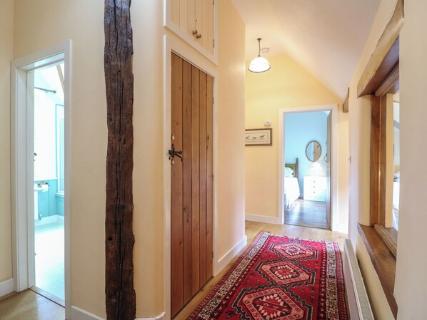 A hallway with a wooden door, a red patterned rug, and a ceiling light. - Just A Cottage, Newlands Farm (Alfreton)