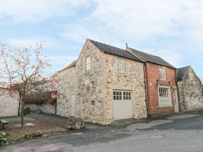 A stone building with a sloped roof, a small window, and a door. - The Old Shop (Ashbourne)