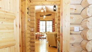 Interior de uma cabana de madeira com área de jantar e um sofá.
