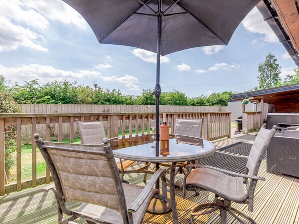 An outdoor patio with a round table, four chairs, and a large umbrella. - Kingfisher Lodge (Driffield)