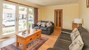 A living room with a sofa, a wooden coffee table, and a patterned rug. - Isla Cottage (Blairgowrie)