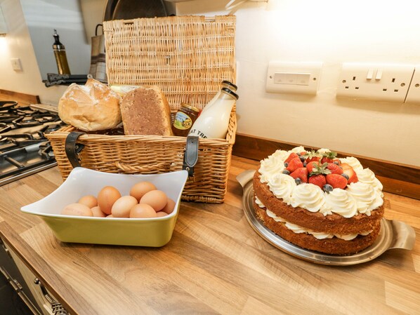 A kitchen counter with a cake topped with strawberries and blueberries, a wicker basket with bread, and a bowl of eggs. - Viaduct House (Lydbrook)