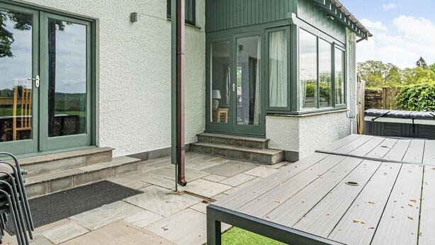 A house with a patio, a door, and a window. - Beech - Woodland Cottages (Windermere)