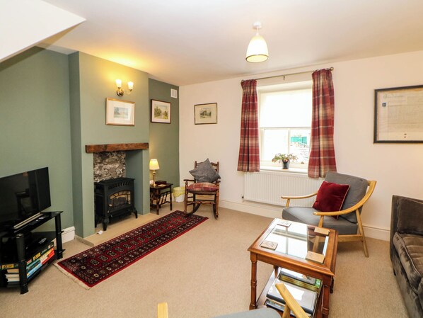 A living room with a fireplace, a television, a sofa, a chair, and a coffee table. - Brookside Barn (Hope Valley)