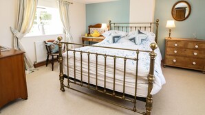A bedroom with a four-poster bed, a wooden dresser, a nightstand, and a mirror on the wall. - Auburn House (York)