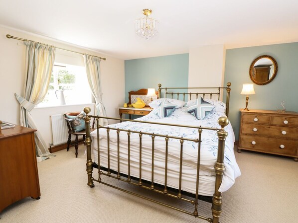 A bedroom with a four-poster bed, a wooden dresser, a nightstand, and a mirror on the wall. - Auburn House (York)