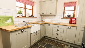 A kitchen with light-colored cabinets, a stone tile floor, and a wooden countertop. - Auburn House (York)