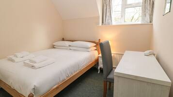Een slaapkamer met een enkel bed, een bureau en een stoel.