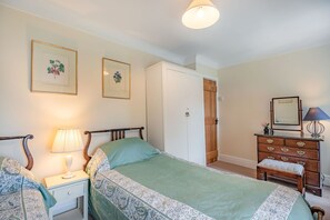 Une chambre à coucher comprenant un lit, une table de chevet, une commode et un miroir.