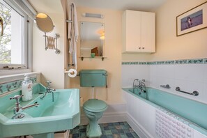 Une salle de bain équipée d’un lavabo, de toilettes et d’une baignoire, avec une décoration aux tons turquoise et des carreaux blancs.