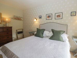 Un dormitorio ordenado con cama, cómoda y toallero de pared.