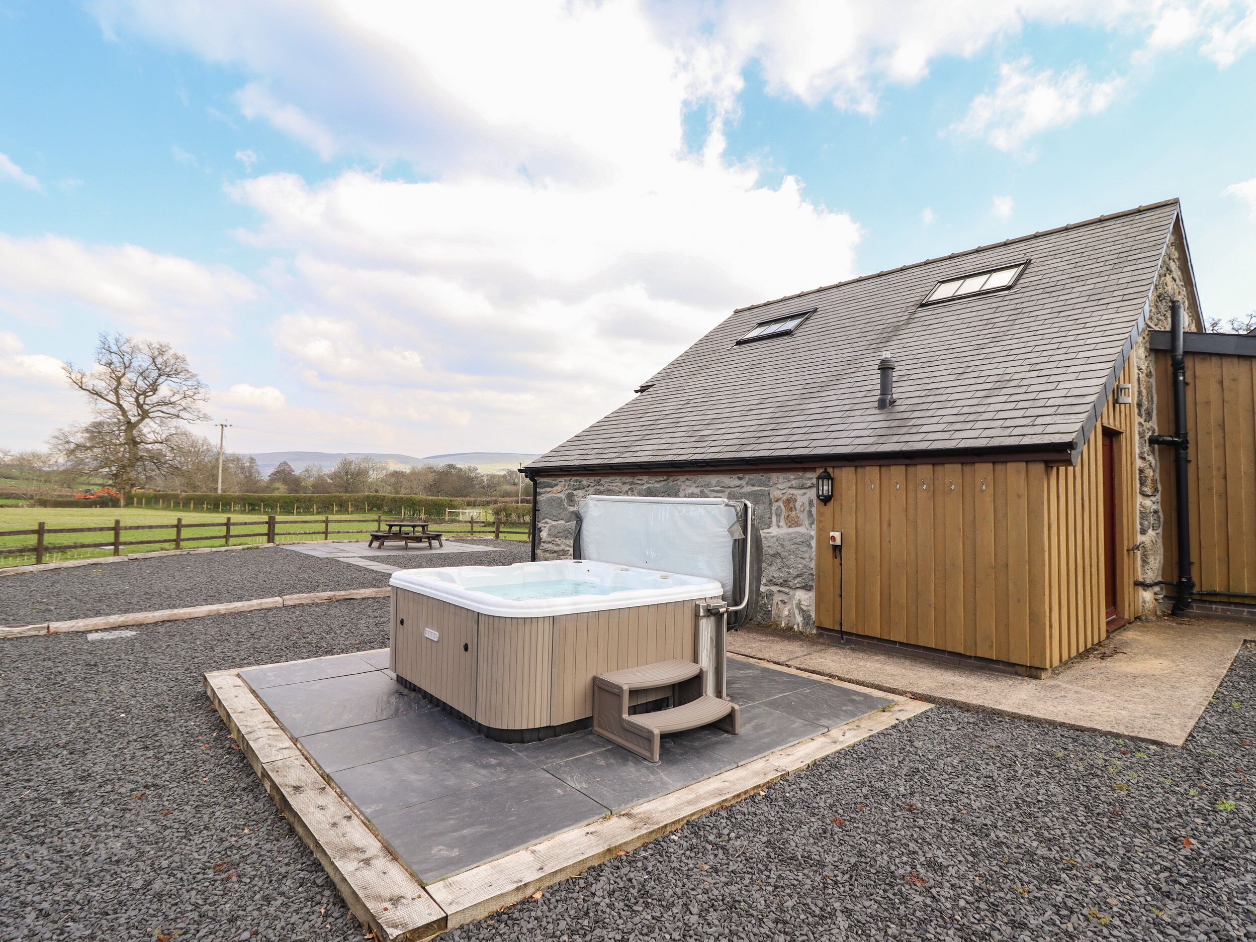 A hot tub and a wooden building with a stone wall and a sloped roof.