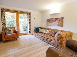 A living room with a brown leather sofa, a brown leather armchair, and a wooden floor.