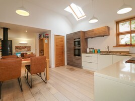 A modern kitchen with wooden cabinets, a built-in oven, and a window with blinds.