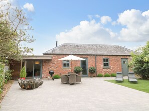 A brick house with a patio, outdoor seating, and a large umbrella.