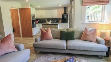 A living room with a grey sofa, a wooden coffee table, and a kitchen in the background.