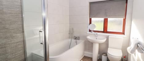 A bathroom with a glass-enclosed shower, a white bathtub, a sink, and a toilet.