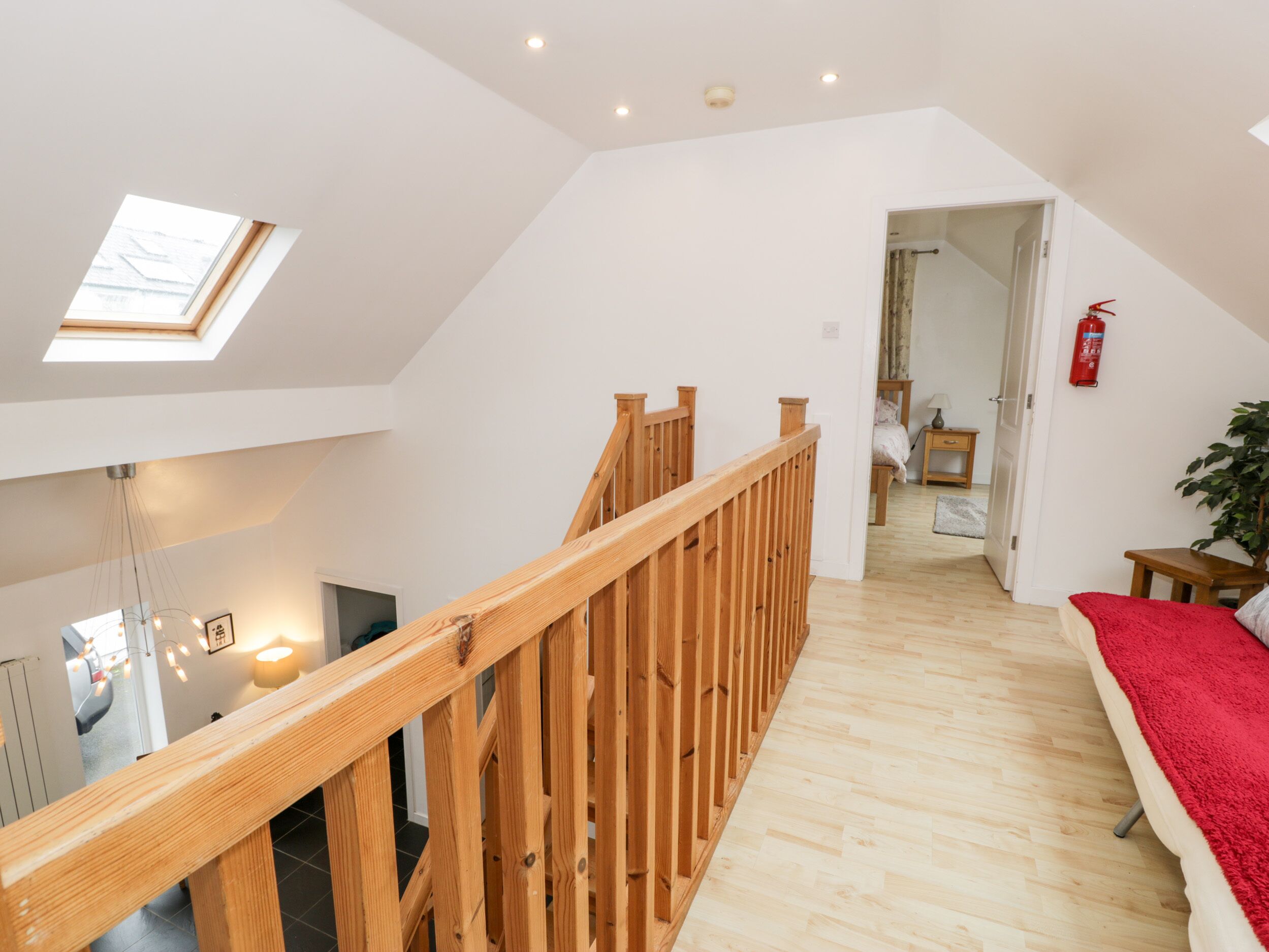 Een ruime loft met een houten trap, een dakraam en een gezellig slaapkamer met een rode deken.