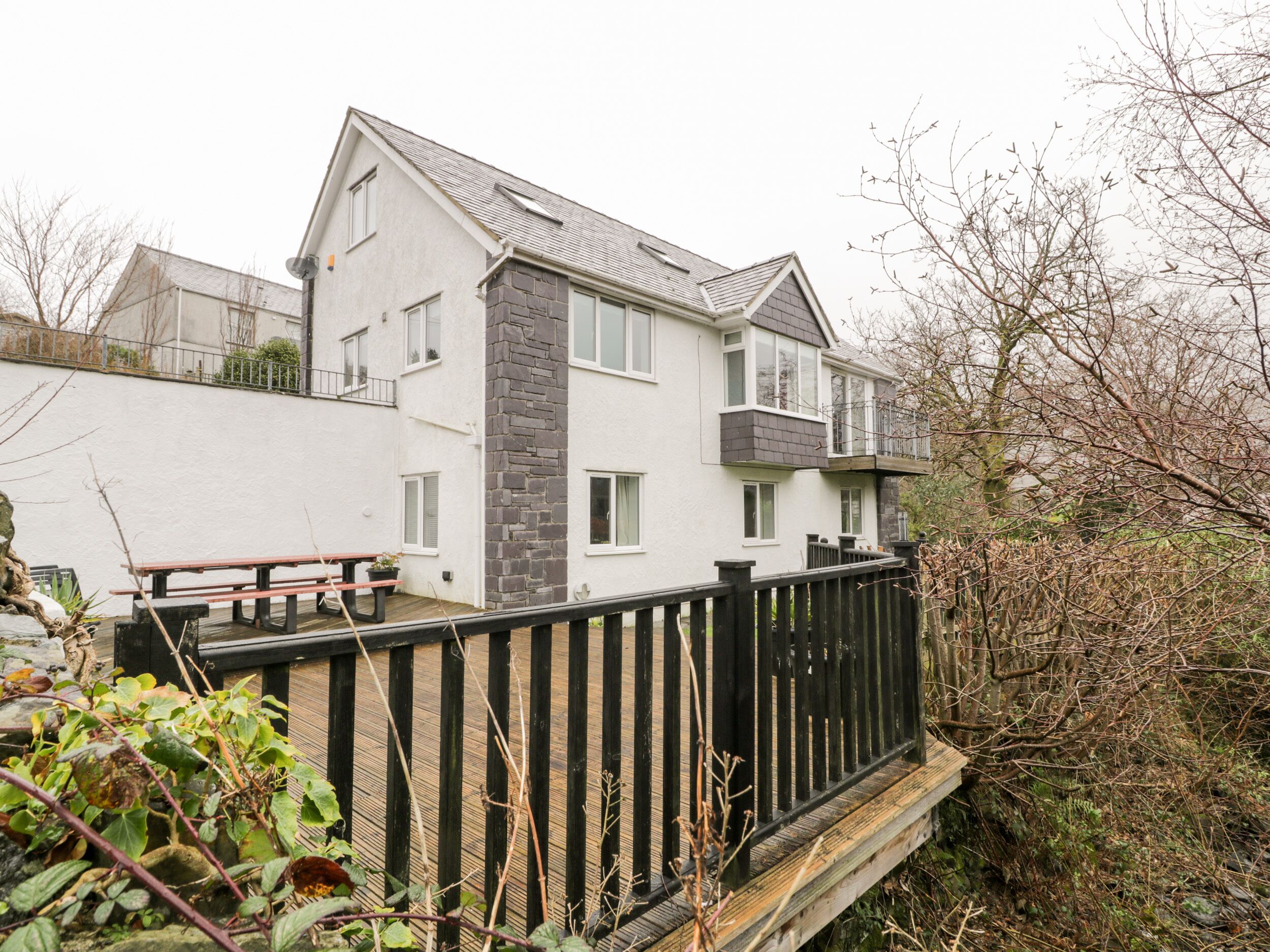 Un immeuble résidentiel de deux étages, doté d’une façade en pierre, d’un balcon et d’une terrasse en bois.