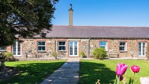 A stone building with a brick facade, a central entrance, and a chimney. - The Shippons (Pwllheli)