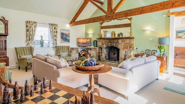 A cozy living room with a fireplace, a television, and a chessboard. - The Shippons (Pwllheli)